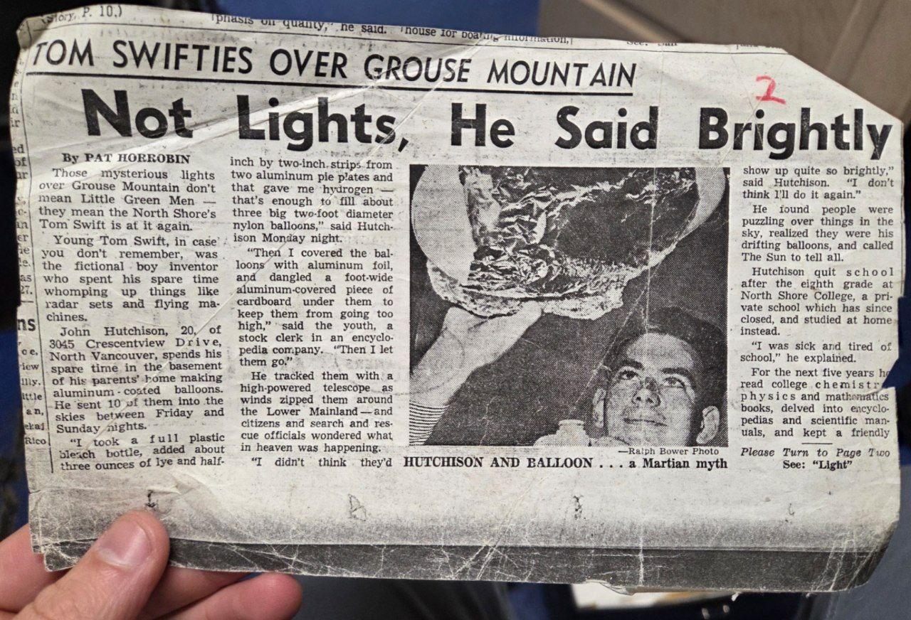 Newspaper clipping headlined "Tom Swifties Over Grouse Mountain: Not Lights, He Said Brightly," about 20-year-old John Hutchison sending hydrogen balloons wrapped in aluminum foil into the sky over North Vancouver in 1965 or 1966, with a photo of Hutchison holding one of the balloons.
